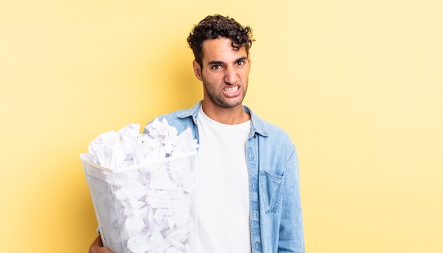 Homem bonito hispânico se sentindo perplexo e confuso. conceito de lixo de bolas de papel