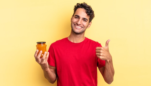 Homem bonito hispânico, sentindo-se orgulhoso, sorrindo positivamente com o polegar para cima. geléia de pêssego