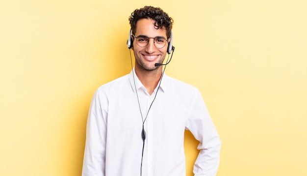 Homem bonito hispânico sorrindo alegremente com uma mão no quadril e confiante. conceito de telemarketing