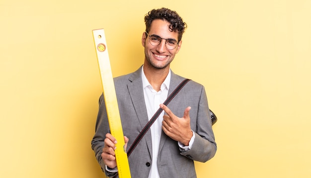 homem bonito hispânico sorrindo alegremente, sentindo-se feliz e apontando para o lado. conceito de arquiteto