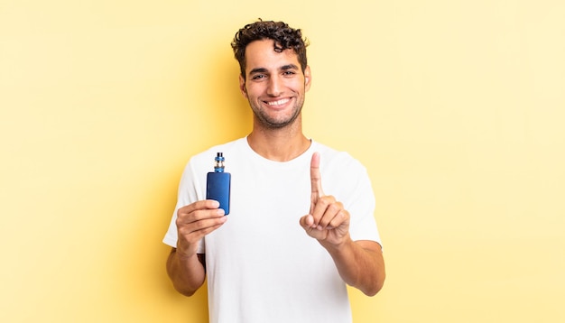 Homem bonito hispânico sorrindo com orgulho e confiança fazendo o número um. conceito de vaporizador