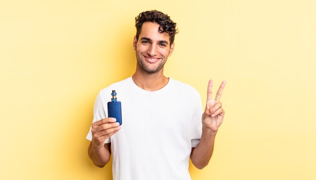 Homem bonito hispânico sorrindo e parecendo amigável, mostrando o número dois. conceito de vaporizador