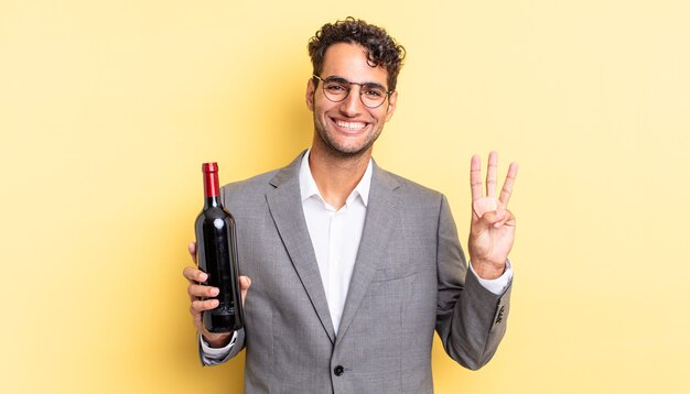 homem bonito hispânico sorrindo e parecendo amigável, mostrando o número três. conceito de garrafa de vinho