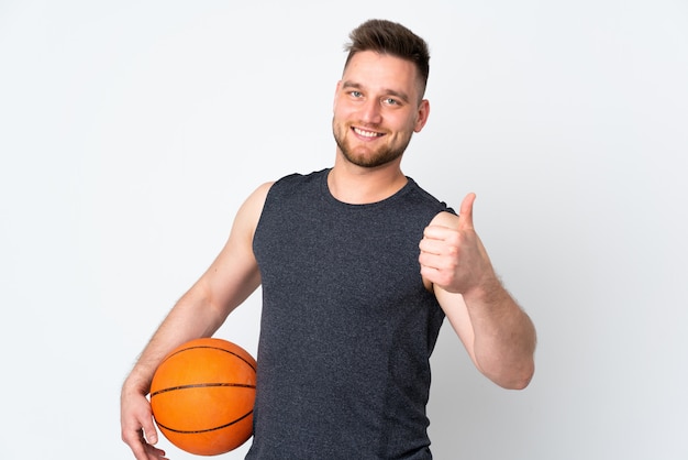 Homem bonito, isolado na parede branca, jogando basquete e com o polegar para cima