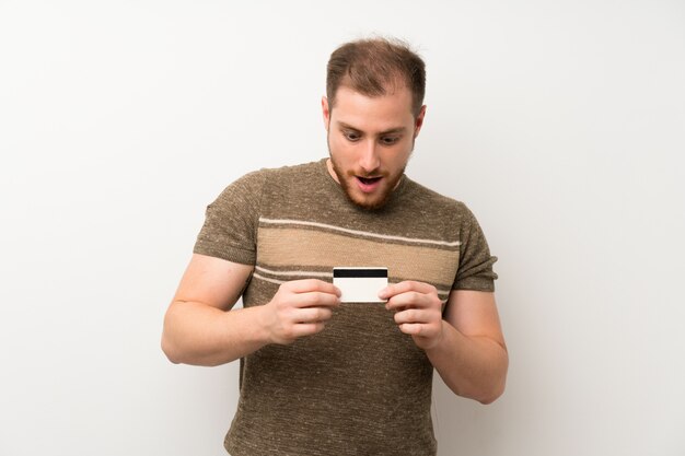 Foto homem bonito isolado parede branca segurando um cartão de crédito