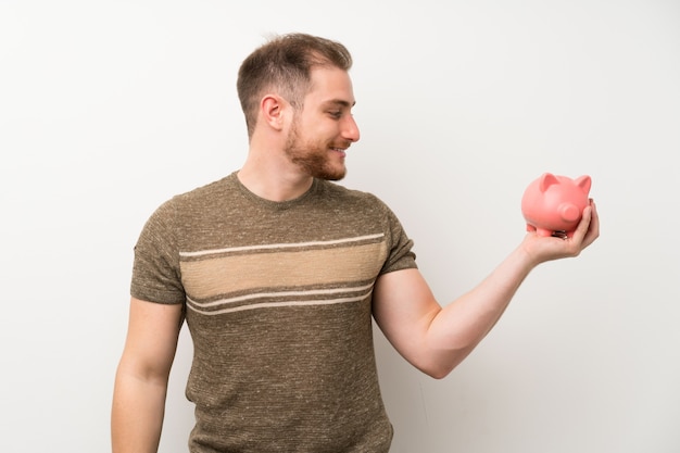 Foto homem bonito isolado parede branca segurando um grande piggybank