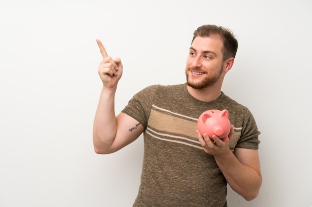 Homem bonito isolado parede branca segurando um grande piggybank