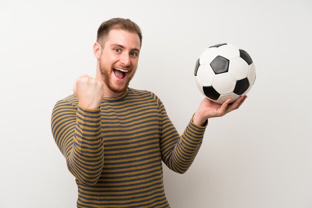 Homem bonito isolado parede branca segurando uma bola de futebol