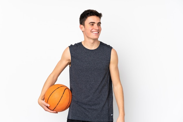 Homem bonito jovem jogador de basquete sobre parede isolada, jogando basquete