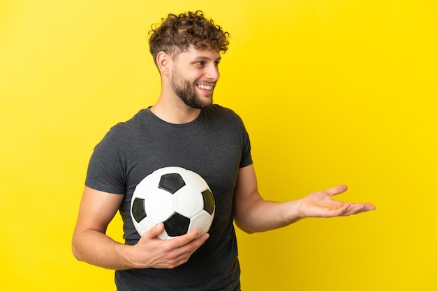 Homem bonito jovem jogador de futebol isolado em um fundo amarelo com expressão de surpresa enquanto olha para o lado