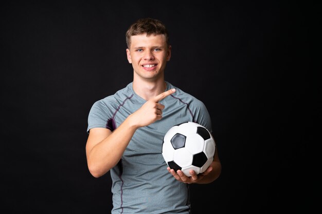 Homem bonito jovem jogador de futebol isolado parede preta