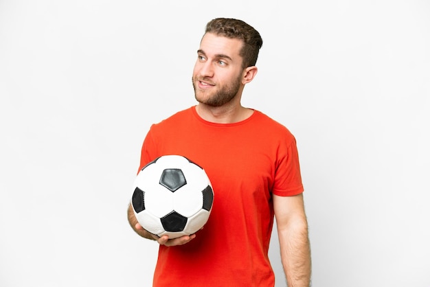 Homem bonito jovem jogador de futebol sobre fundo branco isolado, olhando para o lado e sorrindo