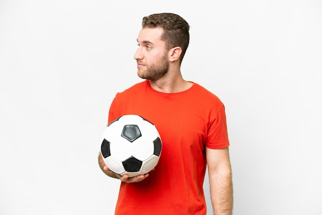 Homem bonito jovem jogador de futebol sobre fundo branco isolado, olhando para o lado