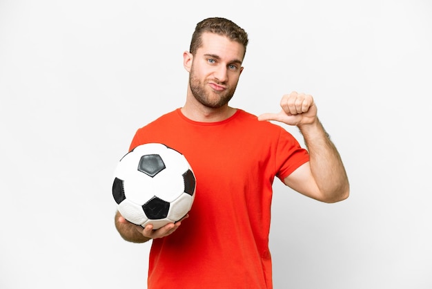 Homem bonito jovem jogador de futebol sobre fundo branco isolado orgulhoso e satisfeito