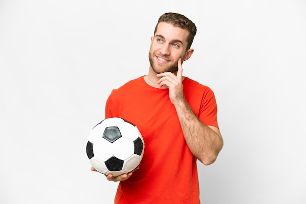 Homem bonito jovem jogador de futebol sobre fundo branco isolado, pensando em uma idéia enquanto olha para cima