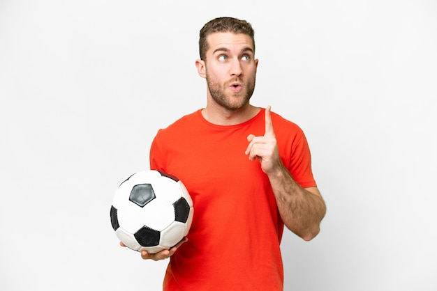 Homem bonito jovem jogador de futebol sobre fundo branco isolado pensando uma idéia apontando o dedo para cima