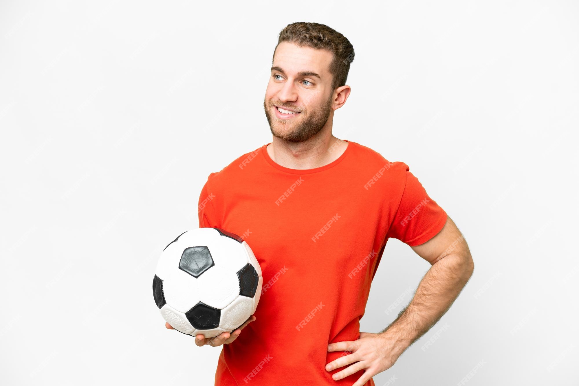 Jogador de futebol forte com bola de futebol e sorrindo em fundo branco  isolado