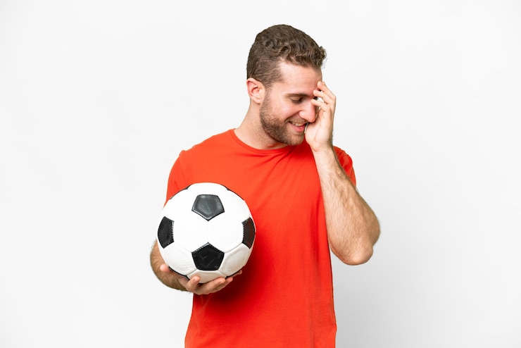 Foto homem bonito jovem jogador de futebol sobre fundo branco isolado rindo