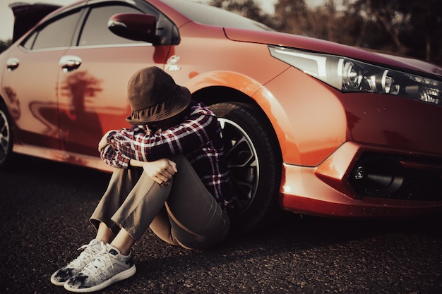 Foto homem bonito jovem sentado ao lado do carro quebrado