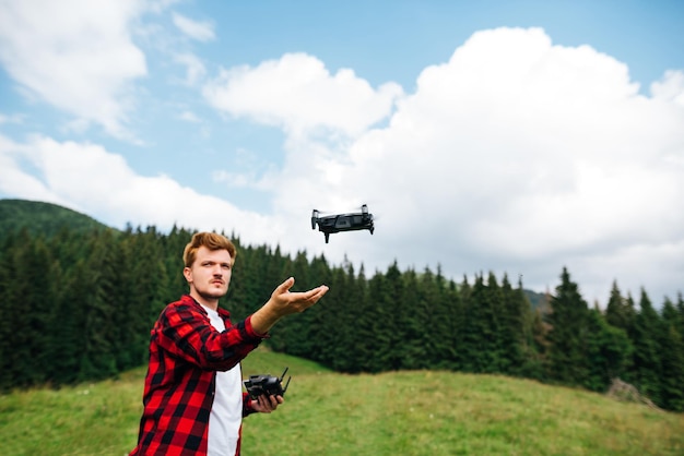 Homem bonito lança drone com as mãos nas montanhas para criar belos vídeos de viagem