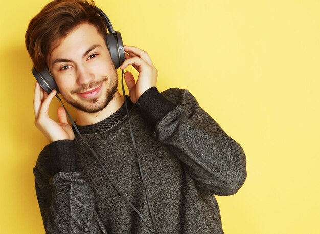 Homem bonito lictening a música sobre fundo amarelo