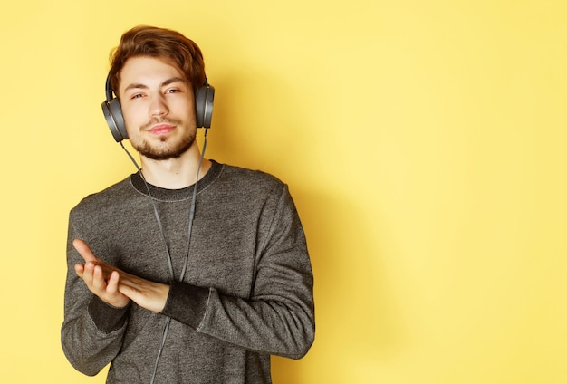 Homem bonito lictening a música sobre fundo amarelo