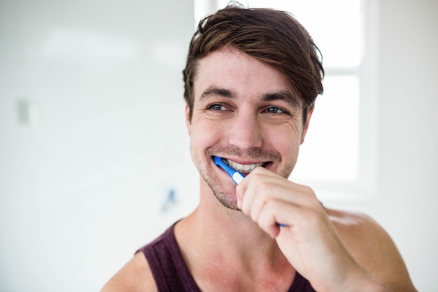 Homem bonito, limpando os dentes no banheiro