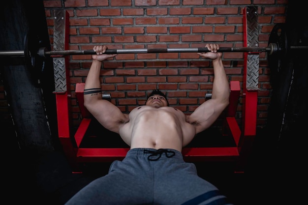 Foto homem bonito malhando na academia homem asiático fazendo levantamento de peso para competir em esportesempurre halteres para treinar os músculos peitorais