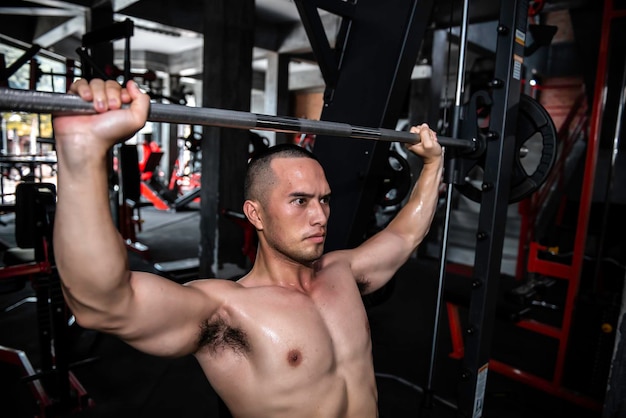 Homem bonito malhando na academia Homem asiático fazendo levantamento de peso para competir em esportesPuxe a barra