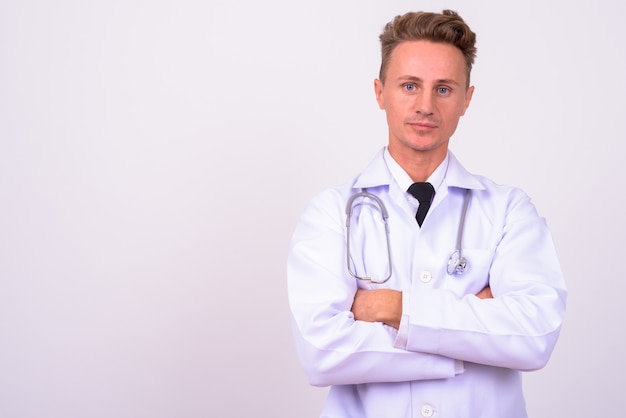 Homem bonito médico com cabelo loiro encaracolado contra uma parede branca