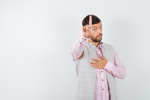 Homem bonito mostrando espera em um gesto de minuto no colete, camisa e parecendo sério,