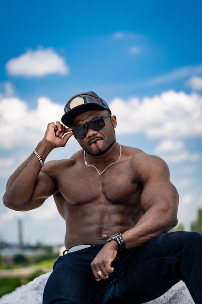 Homem bonito musculoso na vista do céu. Homem sem camisa forte atleta posando para a câmera.