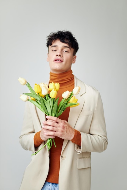 Homem bonito na jaqueta branca com um buquê de flores amarelas estilo elegante estúdio modelo
