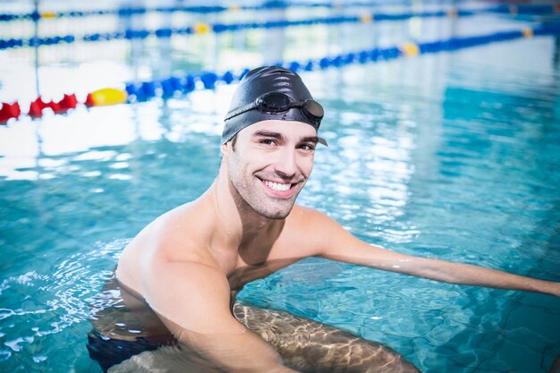 Homem bonito na piscina sorrindo para a câmera