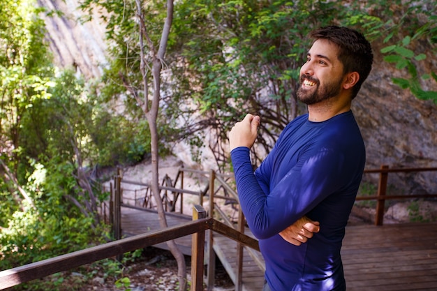 Homem bonito na trilha de férias sorrindo, olhando para a câmera. homem sorrindo no parque. homem cruzar os braços