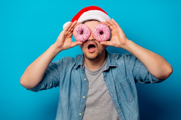 Homem bonito no chapéu de natal com donuts