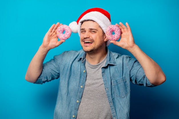 Homem bonito no chapéu de natal com donuts