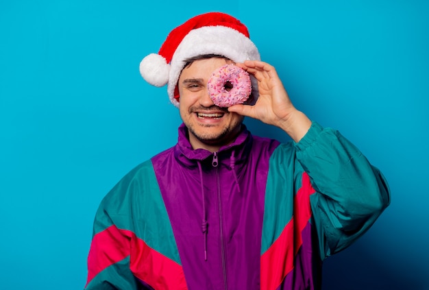 Homem bonito no chapéu de Natal e jaqueta dos anos 90 com donut