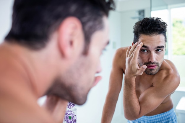 Homem bonito olhando para o cabelo no banheiro