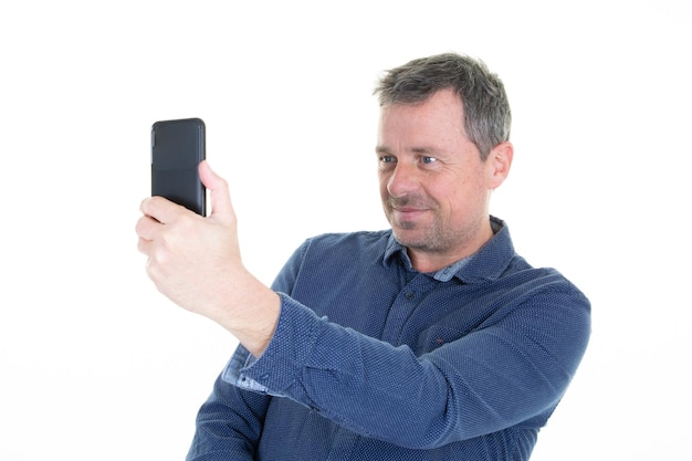 Homem bonito olhando seu celular smartphone fazendo selfie isolado no fundo branco
