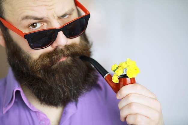 Homem bonito ou hipster barbudo de lenhador com barba e bigode na camisa com cachimbo