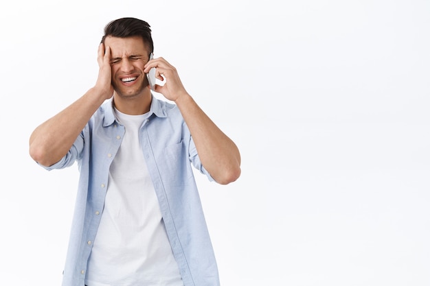 Homem bonito perturbado e chateado esqueceu-se do compromisso, fez uma careta frustrado, tocou a cabeça, conversou por telefone com a pessoa, lembrou-se de uma tarefa importante durante uma chamada de celular