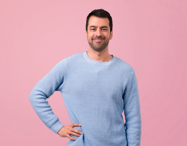 Homem bonito posando com os braços no quadril no fundo rosa