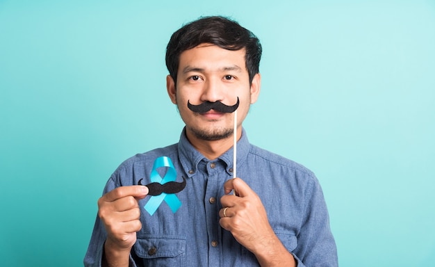 Foto homem bonito posando segurando uma fita azul claro e bigode