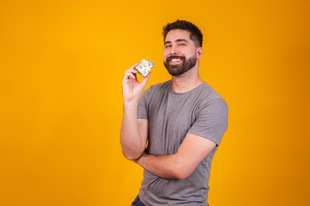 Homem bonito, provando um pedaço de queijo gorgonzola em fundo amarelo