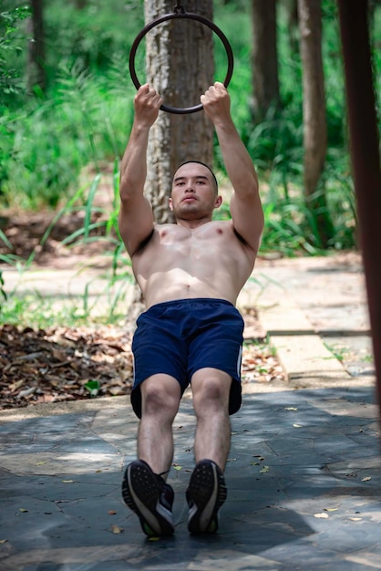 Foto homem bonito se exercita pendurando em um bar ao ar livre, o homem asiático treina para eventos esportivos