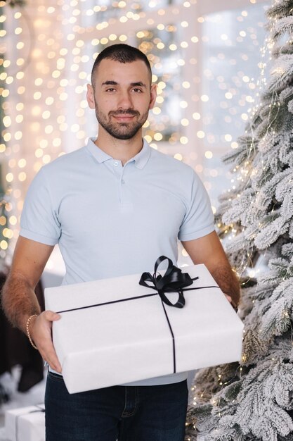 Homem bonito segura grande presente nas mãos clima de natal