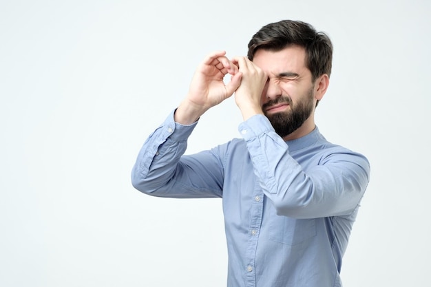 Homem bonito, segurando as mãos nos olhos como se estivesse olhando através de óculos espiões