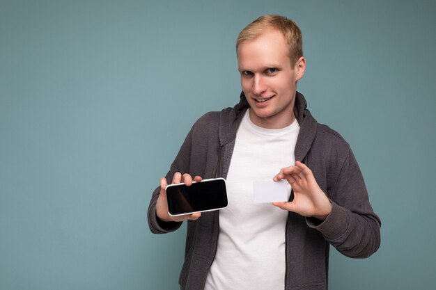 Homem bonito segurando e usando telefone e cartão de crédito