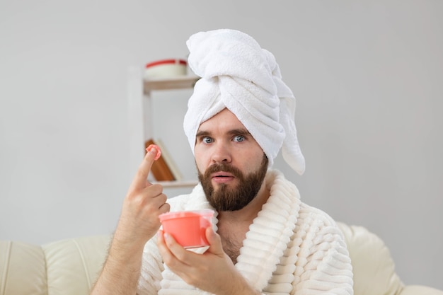 Homem bonito segurando esfoliante rosa cosmético para o corpo do spa da pele e cuidados com a pele para o conceito de homem